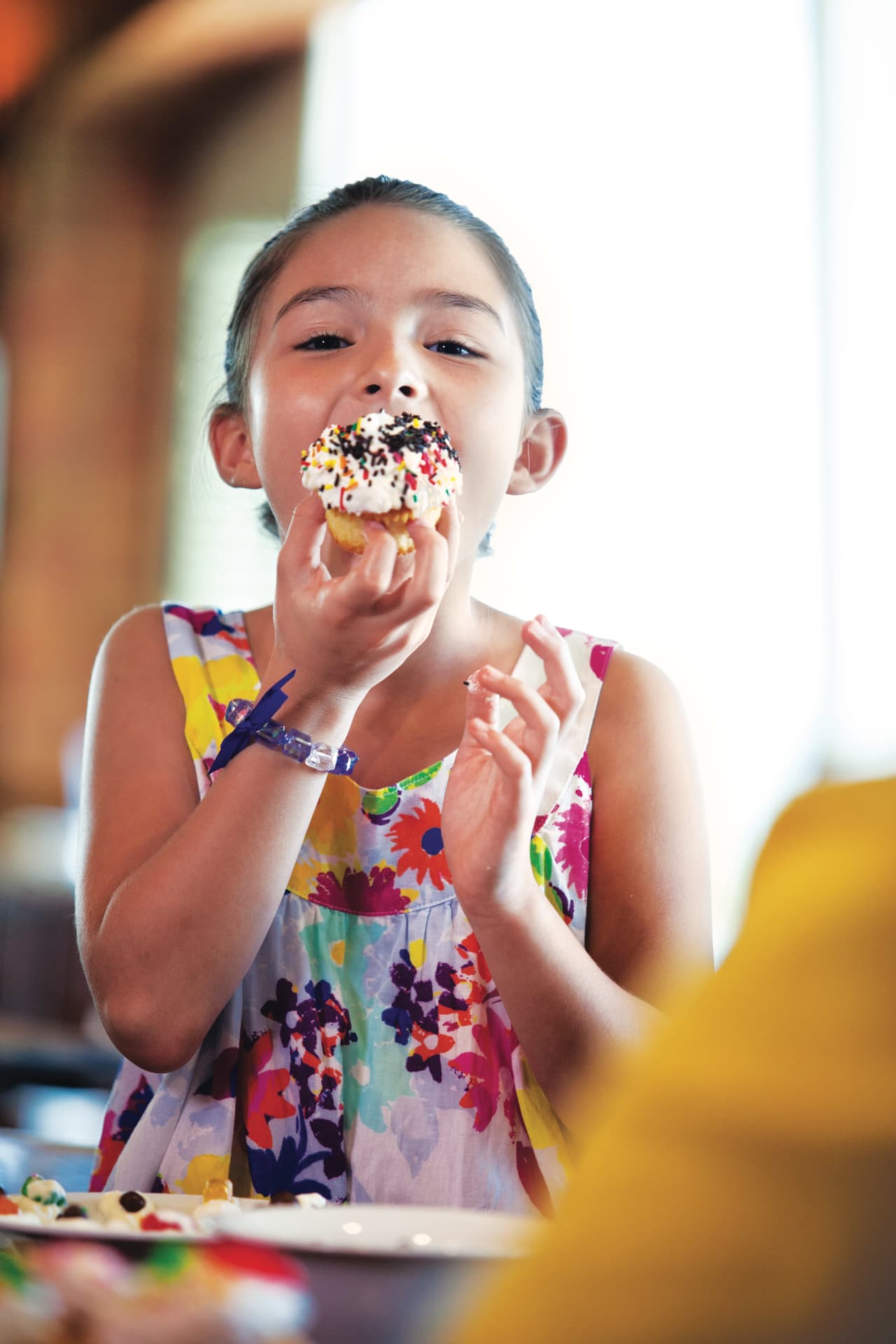 A young girl smiling as she eats a frosted cupcake onboard