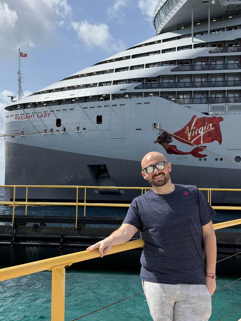 Chris standing in front of the Virgin Voyages ship Valiant Lady.