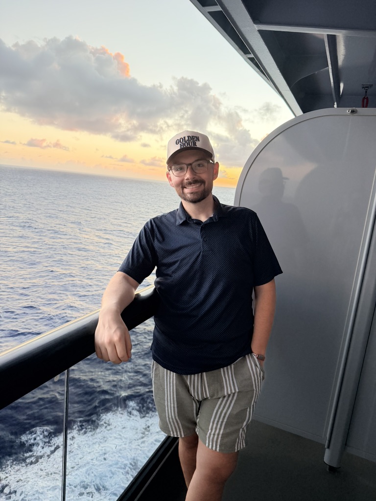 Chris Groleau on a cruise ship deck as the sun sets over the water.