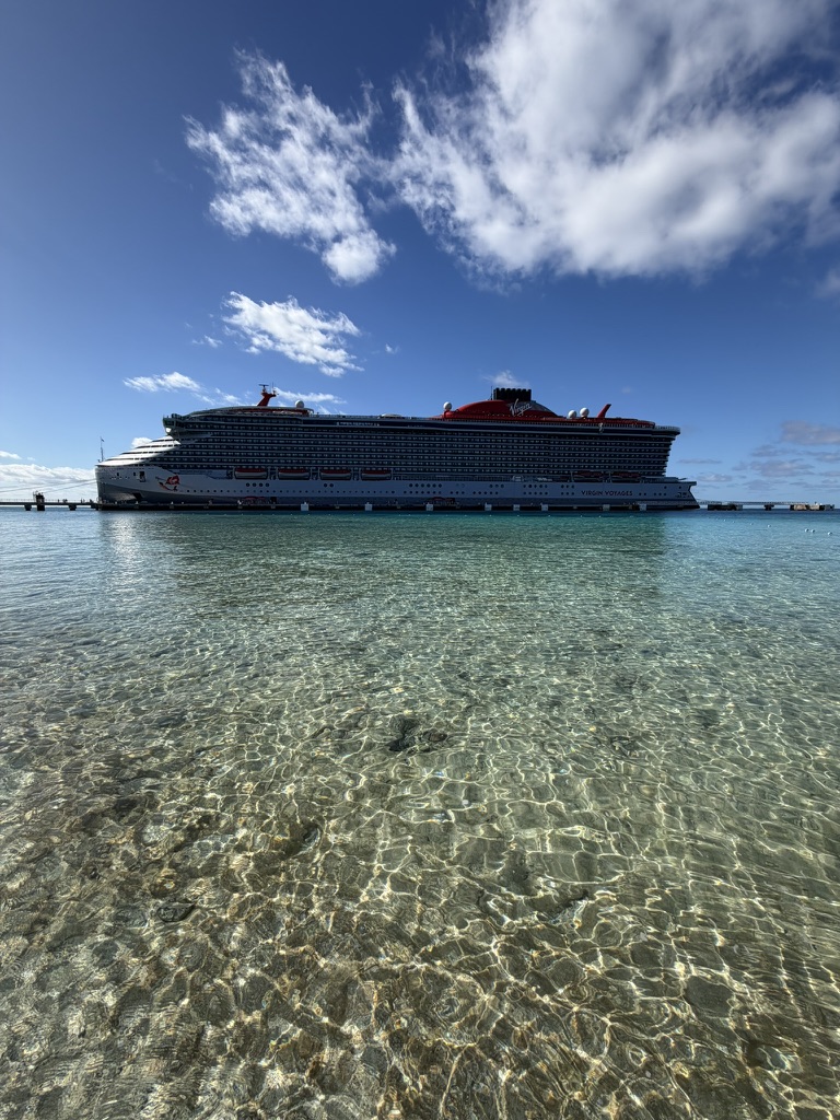 A cruise ship sailing on open ocean water in warm late-day light.