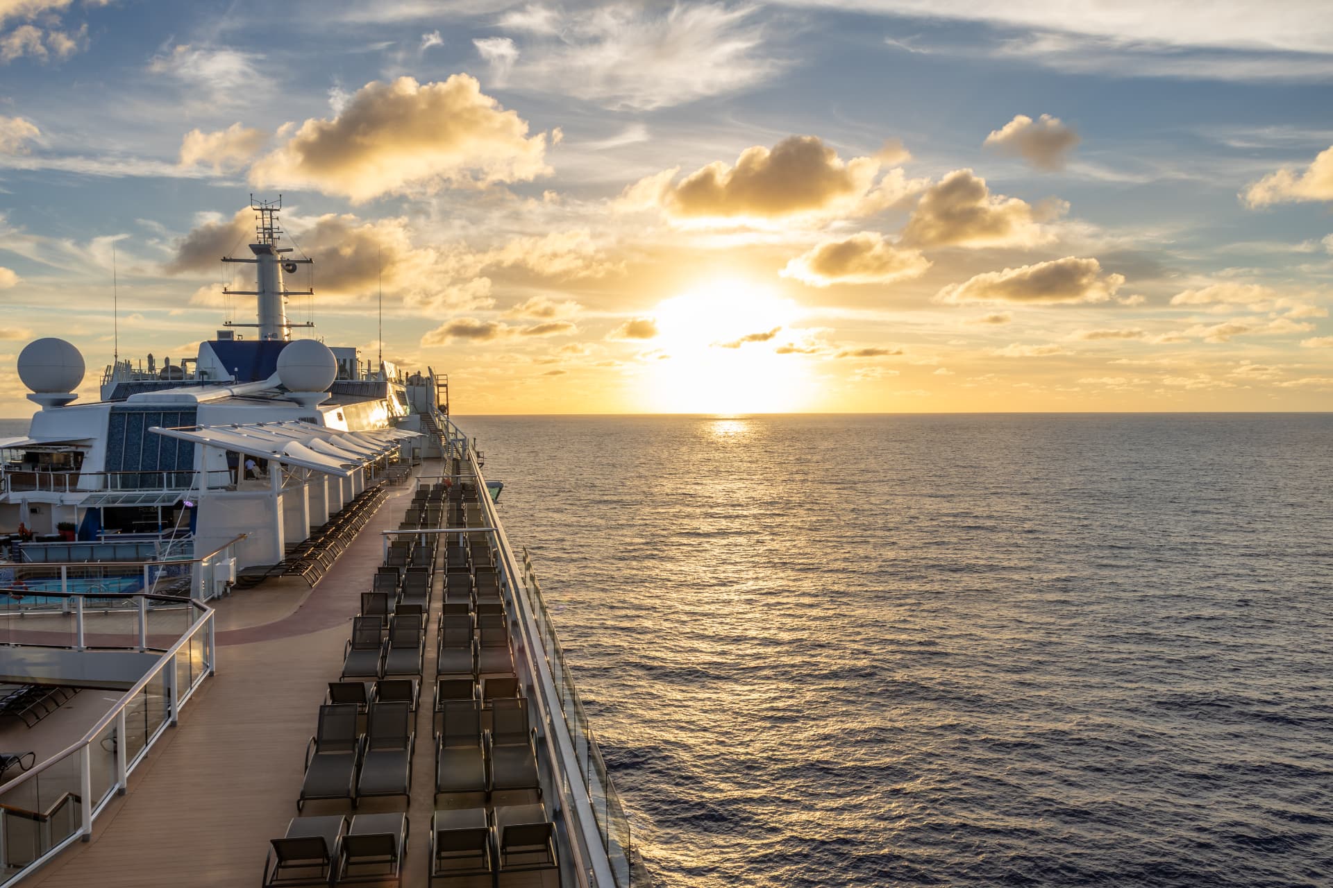 A warm sunset viewed across the ocean from a cruise-ship deck.