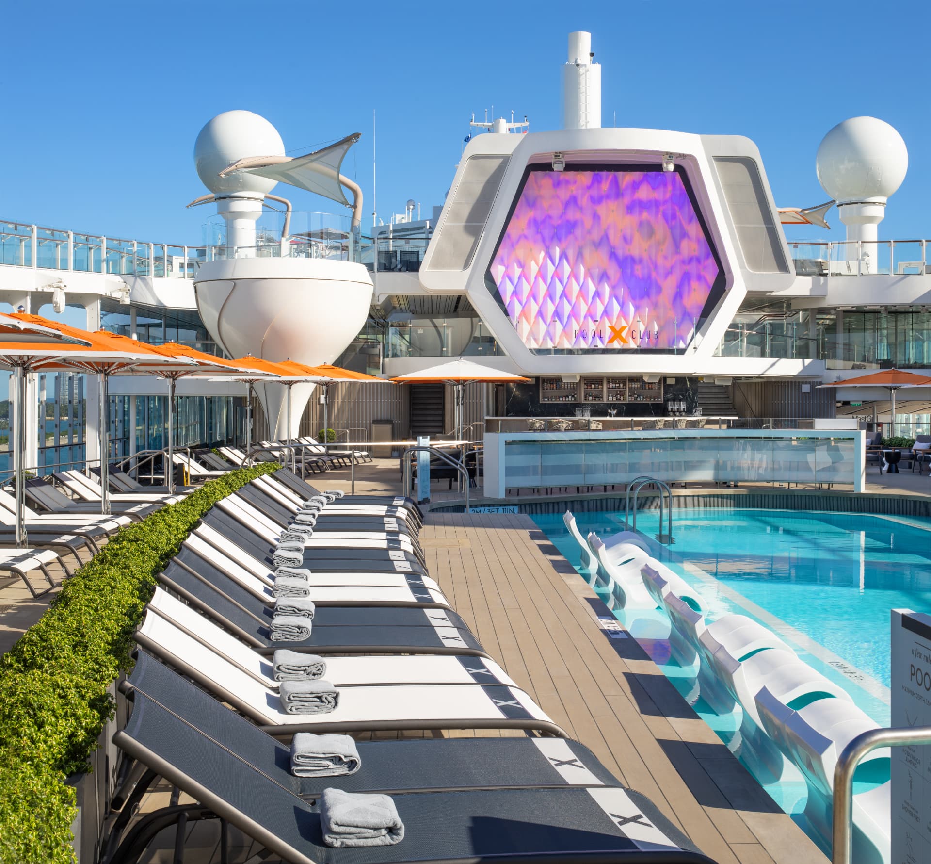 An outdoor pool area aboard a cruise ship overlooking the ocean.